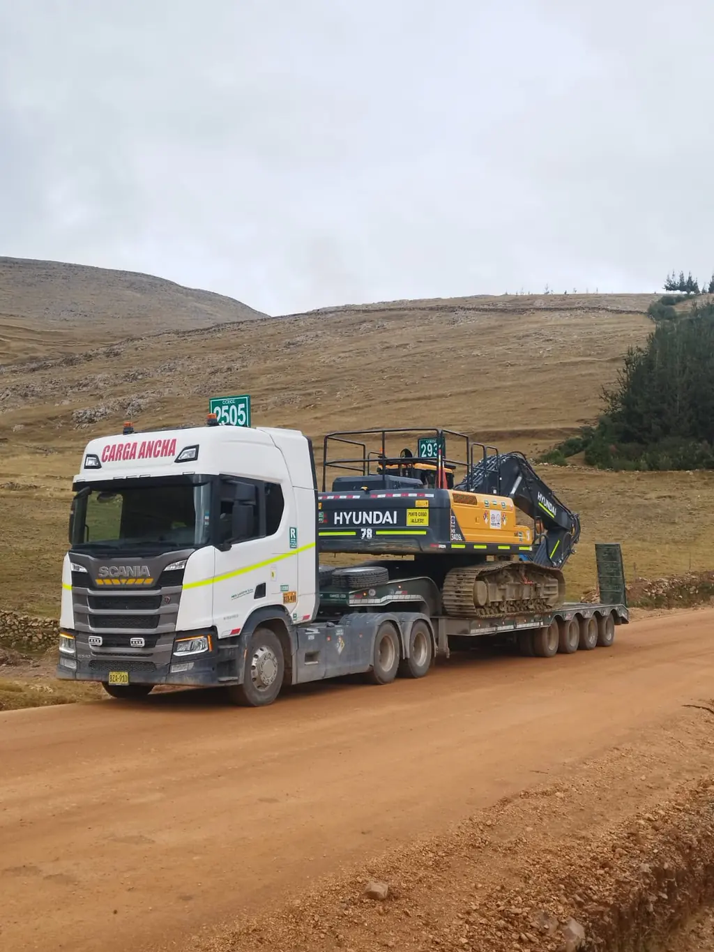 Tracto Scania con excavadora Hyundai sobre cama baja en vía afirmada