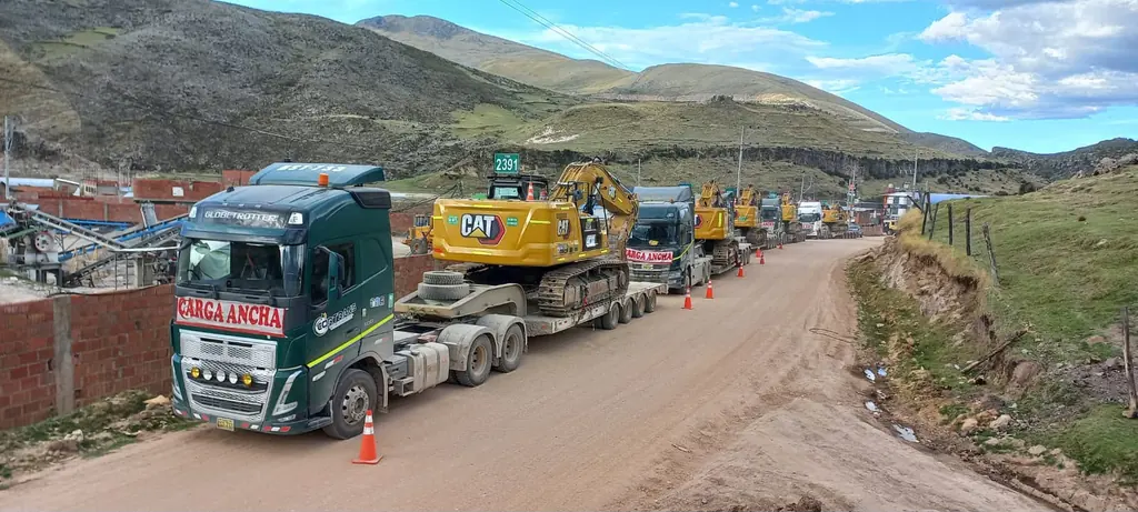 Convoy de camas bajas con excavadoras CAT en vía rural