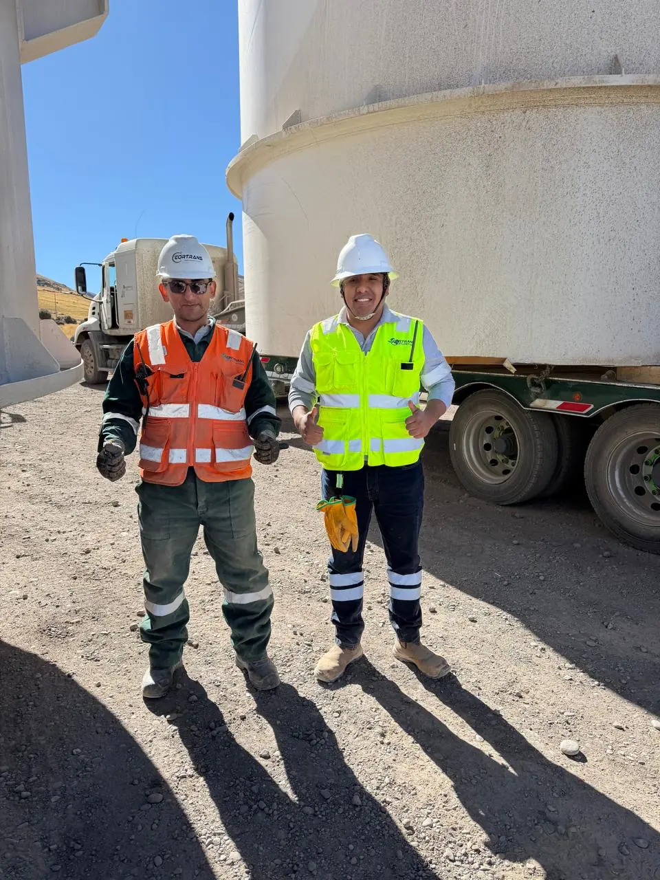 Dos supervisores con equipo de protección frente a un tanque cargado