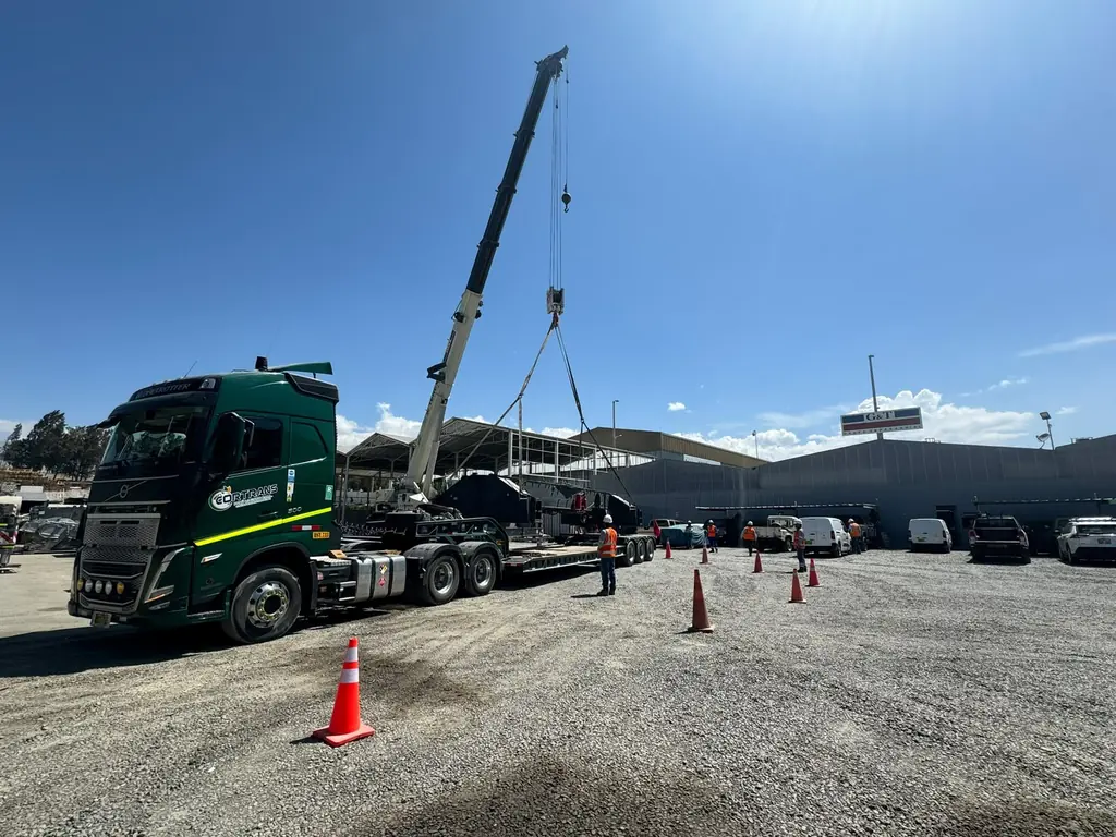 Grúa izando carga sobre un tracto de CORTRANS en patio de operaciones